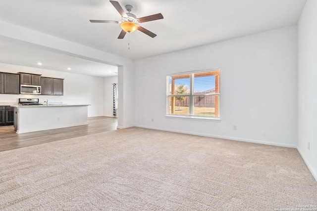 unfurnished living room featuring light carpet and ceiling fan