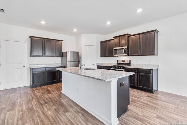 3146 Jackson Smt, Converse, TX 78109 - kitchen featuring appliances with stainless steel finishes, light wood finished floors, dark brown cabinets, a kitchen island with sink, and recessed lighting