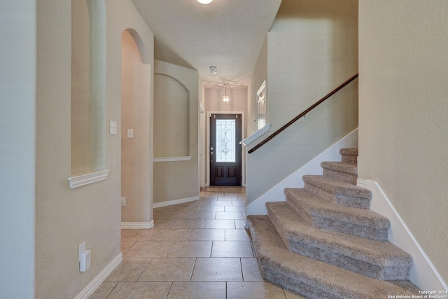 foyer entrance with light tile patterned floors and a textured ceiling