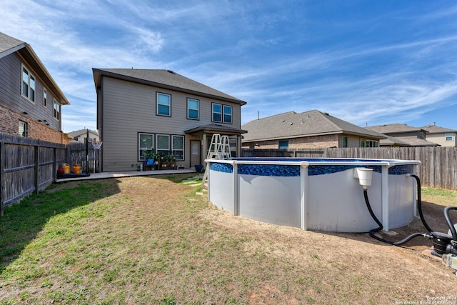 rear view of house featuring a fenced in pool and a lawn