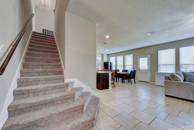 stairs featuring a textured ceiling and tile patterned floors