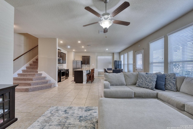 tiled living room with ceiling fan, sink, and a textured ceiling