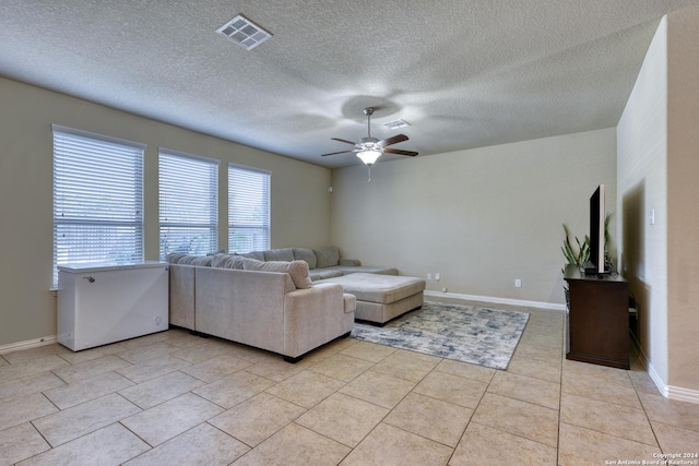 unfurnished living room featuring ceiling fan, light tile patterned floors, and a textured ceiling