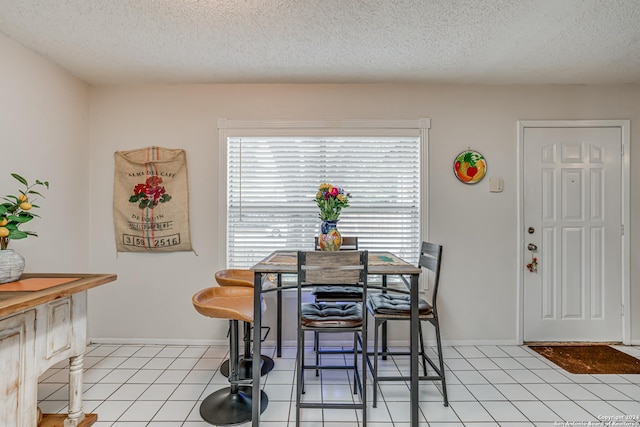 tiled dining room featuring a textured ceiling