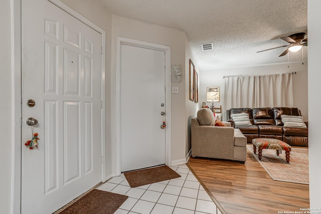 foyer entrance with ceiling fan, a textured ceiling, and light hardwood / wood-style flooring