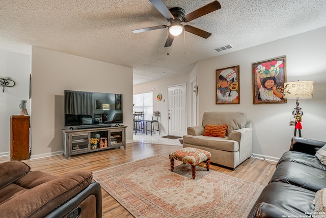 living room with ceiling fan, light hardwood / wood-style flooring, and a textured ceiling