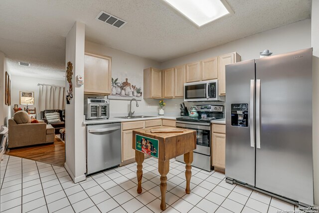 kitchen featuring light brown cabinetry, sink, a textured ceiling, and appliances with stainless steel finishes