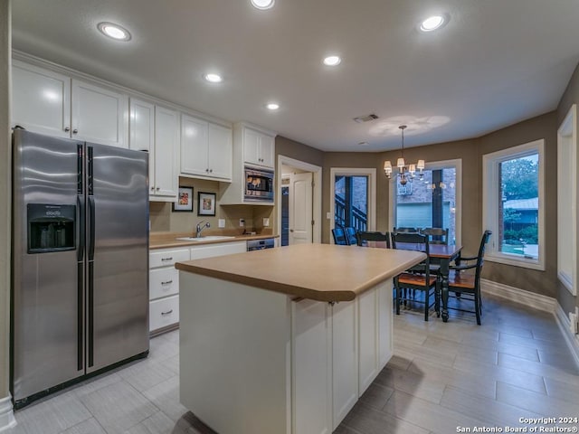 kitchen featuring a center island, an inviting chandelier, hanging light fixtures, white cabinetry, and stainless steel appliances