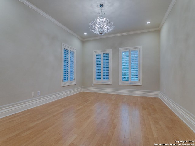 spare room featuring light wood-type flooring, an inviting chandelier, and crown molding