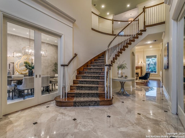 stairs with crown molding, french doors, and a towering ceiling