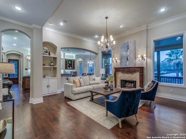 living room featuring ornamental molding, an inviting chandelier, dark wood-type flooring, and a premium fireplace