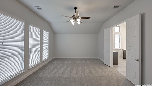 bonus room with vaulted ceiling, plenty of natural light, and light colored carpet