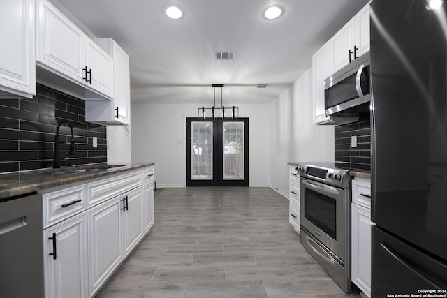 kitchen featuring sink, hanging light fixtures, tasteful backsplash, white cabinets, and appliances with stainless steel finishes