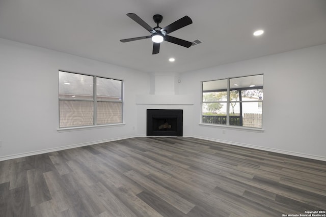 unfurnished living room with ceiling fan, a large fireplace, and dark hardwood / wood-style floors