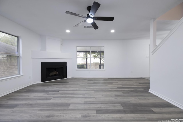 unfurnished living room with hardwood / wood-style floors, ceiling fan, and a large fireplace