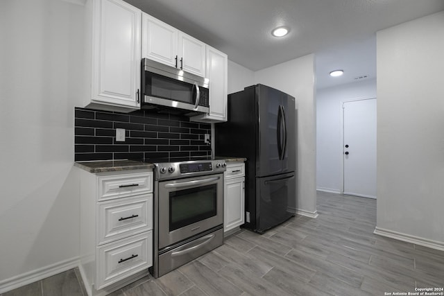 kitchen with appliances with stainless steel finishes, light hardwood / wood-style flooring, white cabinetry, and tasteful backsplash