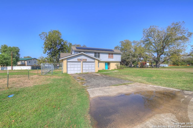 view of front of house with a garage, a front yard, and solar panels