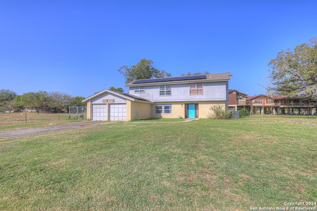 front of property with a front yard, solar panels, and a garage