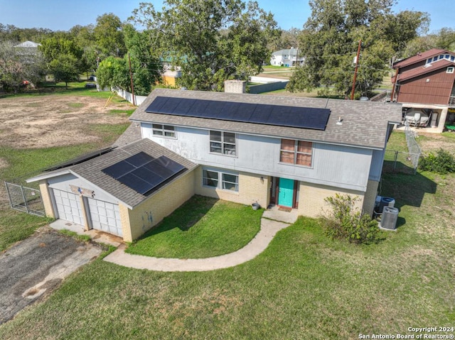 back of property with solar panels, a garage, a lawn, and central air condition unit