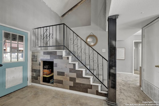 staircase featuring concrete flooring, a textured ceiling, and vaulted ceiling