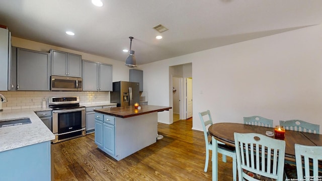 kitchen featuring a center island, stainless steel appliances, tasteful backsplash, dark hardwood / wood-style floors, and butcher block countertops