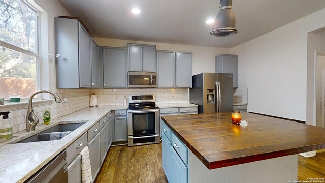 kitchen with sink, dark wood-type flooring, wood counters, backsplash, and appliances with stainless steel finishes