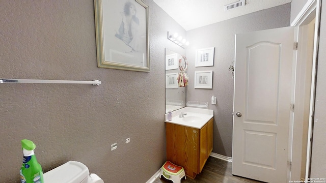 bathroom with hardwood / wood-style flooring, vanity, and toilet