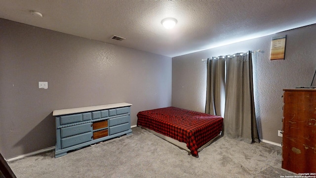 bedroom with light colored carpet and a textured ceiling