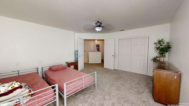 bedroom featuring carpet flooring, ceiling fan, a textured ceiling, and a closet