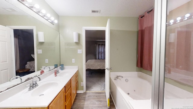 bathroom with hardwood / wood-style floors, vanity, a textured ceiling, and a bathtub