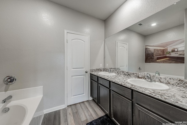 bathroom featuring vanity, wood-type flooring, and a bath