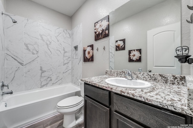 full bathroom with vanity, toilet, tiled shower / bath, and hardwood / wood-style flooring