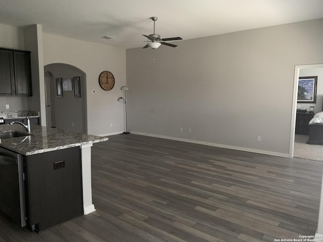 kitchen with dark stone counters, ceiling fan, sink, dishwasher, and dark hardwood / wood-style floors