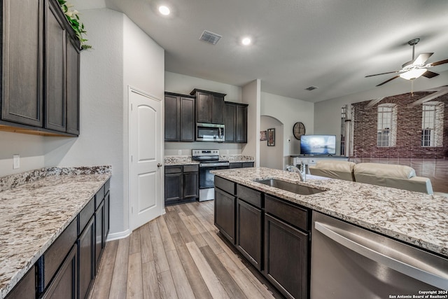 kitchen featuring dark brown cabinetry, sink, stainless steel appliances, light stone counters, and light hardwood / wood-style flooring