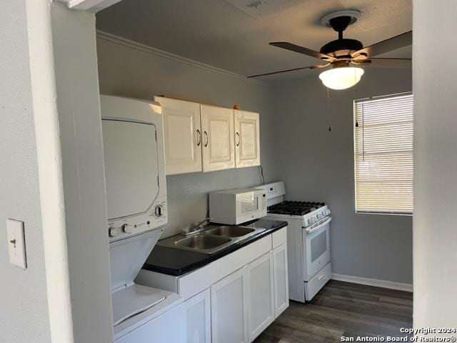 kitchen with white appliances, sink, stacked washer / dryer, white cabinets, and dark hardwood / wood-style floors