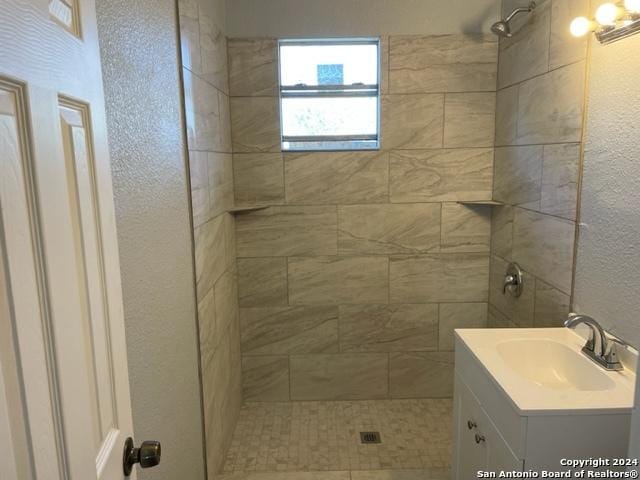 523 Bee St, San Antonio, TX 78208 - bathroom featuring a tile shower, a textured wall, and vanity