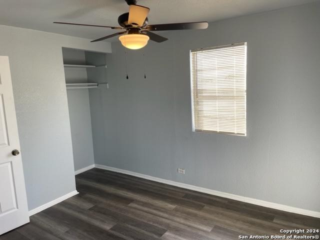 523 Bee St, San Antonio, TX 78208 - unfurnished bedroom featuring dark wood finished floors, baseboards, a closet, and ceiling fan