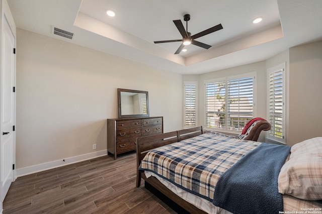 bedroom featuring dark hardwood / wood-style floors, ceiling fan, and a raised ceiling