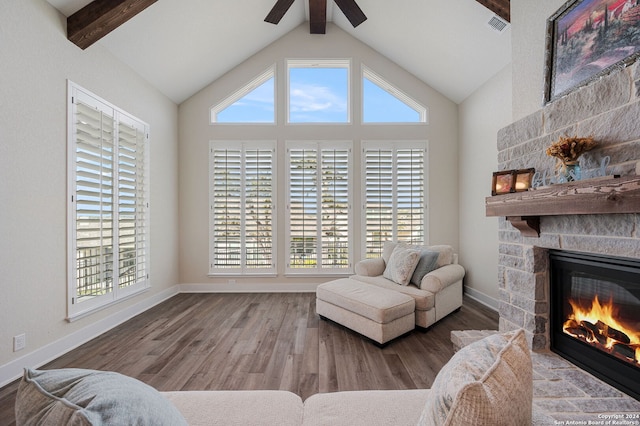 sitting room featuring hardwood / wood-style floors, high vaulted ceiling, a stone fireplace, and beam ceiling