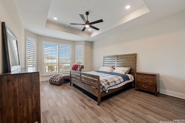 bedroom featuring ceiling fan, a raised ceiling, and wood-type flooring