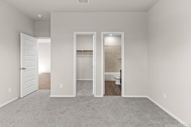 unfurnished bedroom with ensuite bathroom, a spacious closet, and carpet floors