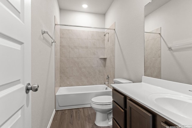 full bathroom featuring hardwood / wood-style flooring, tiled shower / bath combo, toilet, and vanity