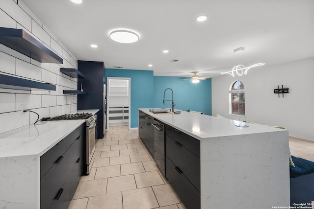 kitchen featuring appliances with stainless steel finishes, ceiling fan, sink, decorative light fixtures, and a large island