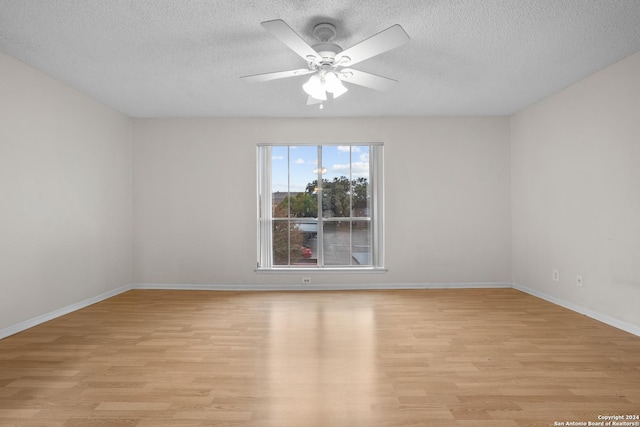 unfurnished room with a textured ceiling, light wood-type flooring, and ceiling fan