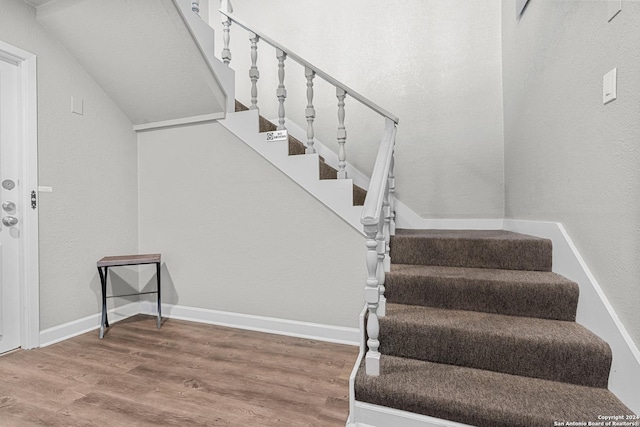 stairs with wood-type flooring and vaulted ceiling