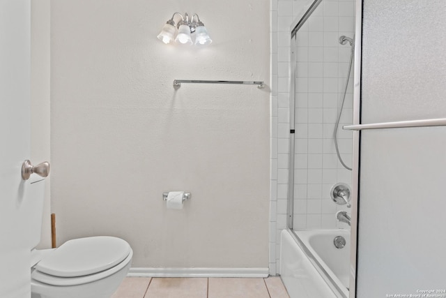 bathroom with tile patterned floors, tiled shower / bath combo, and toilet