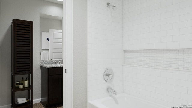 bathroom with tiled shower / bath combo and vanity