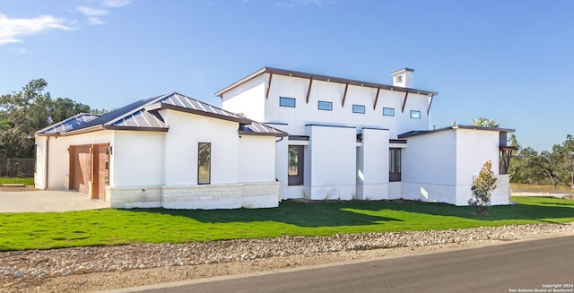 view of front of home featuring driveway, metal roof, an attached garage, a standing seam roof, and a front yard