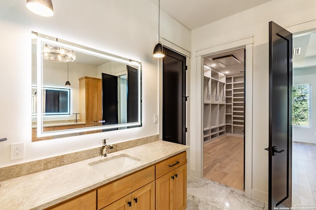 bathroom with marble finish floor, a walk in closet, and vanity