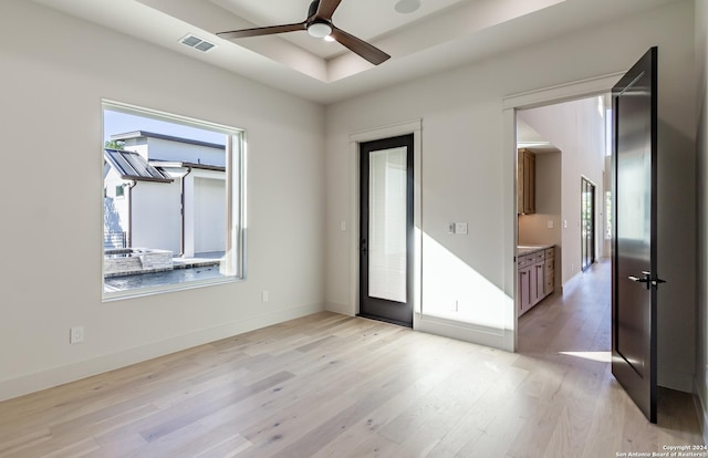 spare room with a healthy amount of sunlight, light wood-style flooring, visible vents, and ceiling fan